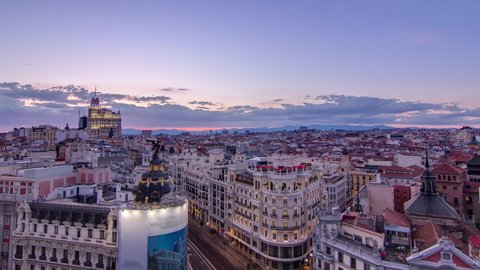 Panoramic aerial view of Gran Via day to night transition, main shopping street in Madrid Skyline Old Town Cityscape, Metropolis Building lights turn on, capital of Spain, Europe.