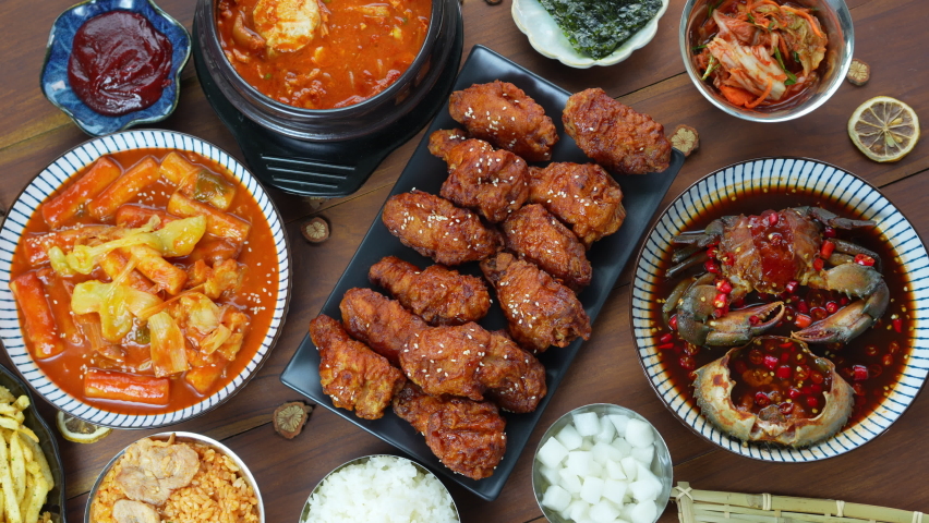 Traditional Korean food, Korean Fried chicken with spicy sauce  with rice, seaweed,fresh raw crabs marinated,spicy Rice Cake and Kimchi pickle on wooden table. Royalty-Free Stock Footage #1084694344