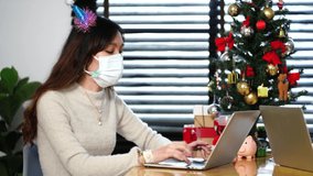 Asian women wear masks, hair clips, Christmas accessories and work with laptops during the New Year holidays. 