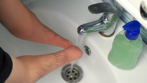Disabled man with amputated two stump hands is washing his hands with soap at home in bathroom in sink, closeup view. Everyday routine life of a handicapped guy person with disabilities.