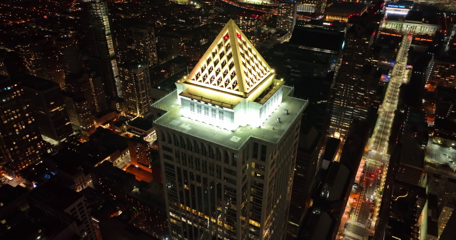 Phi , PA , United States - 11 28 2021: Cinematic aerial of skyscraper tower at night. Tilt up reveals cityscape lights and traffic. Birds eye drone view.