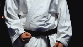 Man in a vibrant white karate uniform, isolated by darkness, shows respect by bowing - Powered by Shutterstock - Get 15% off with code: PIKWIZARD15