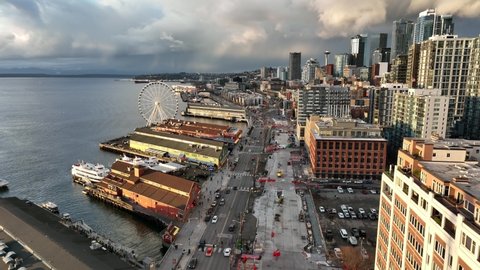 Birdseye drone dolly shot of the Seattle Great Wheel with downtown waterfront, Bainbridge Ferry Terminal, Alaskan Way and the Seattle Aquarium