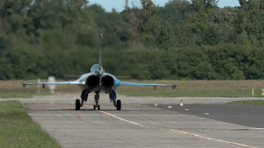 Hot air coming from stationary fighter jet standing on runway, sunny day