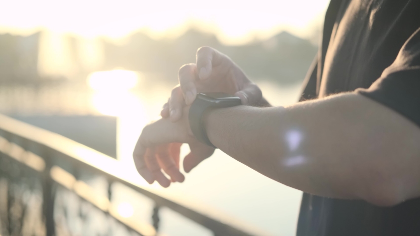 Asian men going to exercise by running at the park in the morning at sunrise  Smart watch. Smart watch on a man's hand outdoor. Man's hand touching a smart watch to press start to recording