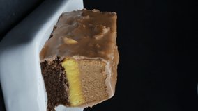 a shiny spoon breaks off a cake with a three-layer mango filling and covered with milk chocolate with waffle pieces. vertical screen orientation. Dolly movement