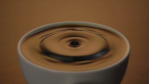 Espresso coffee drop into the filled cup in slow motion
