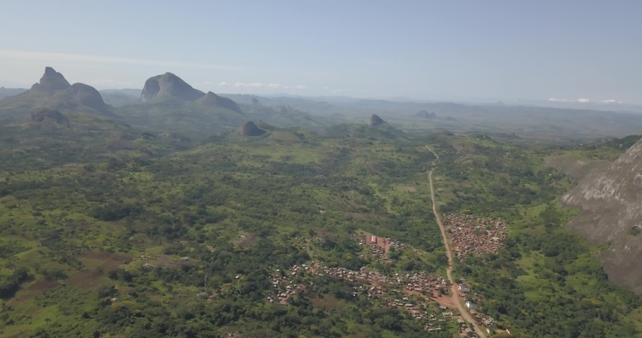 Aerial drone footage of a tropical landscape, with forest and mountains Kumbira forest reserve, small village and huge geologic rock elements, on Conda, Sumbe, Angola...