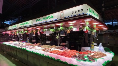 Barcelona, Catalonia, Spain - December 27, 2021: Local fresh fish and seafood stand at famous Mercado de La Boqueria market. Workers prepare fish for selling and placing on display. Fish on ice. 