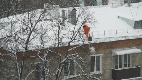 One worker of snow cleaning public utility on the roof