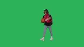 Teen girl with backpack and basketball walking on Green Screen, Chroma Key. Perspective view 4k uhd video footage