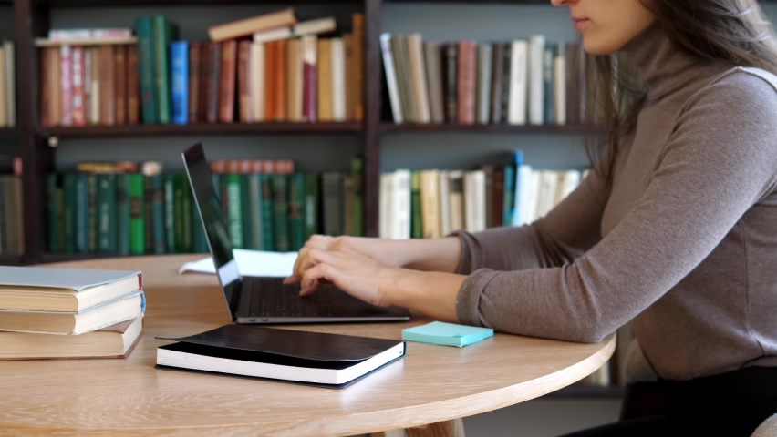 College student uses a laptop to watch online distance learning, a seminar, a distance university webinar, or conduct a virtual classroom meeting in the university's creative space. The girl works on Royalty-Free Stock Footage #1084738177