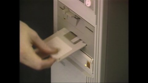 1980s Cupertino, CA. Motion Graphics Designer works on IBM Computer with stylist. Close Up of 3½-inch floppy disks inserted into Hard Drive. 4K Scan of Vintage Archival Betacam Master