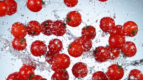 Super Slow Motion Shot of Flying Fresh Tomatoes with Water Splashing on White Background at 1000fps.