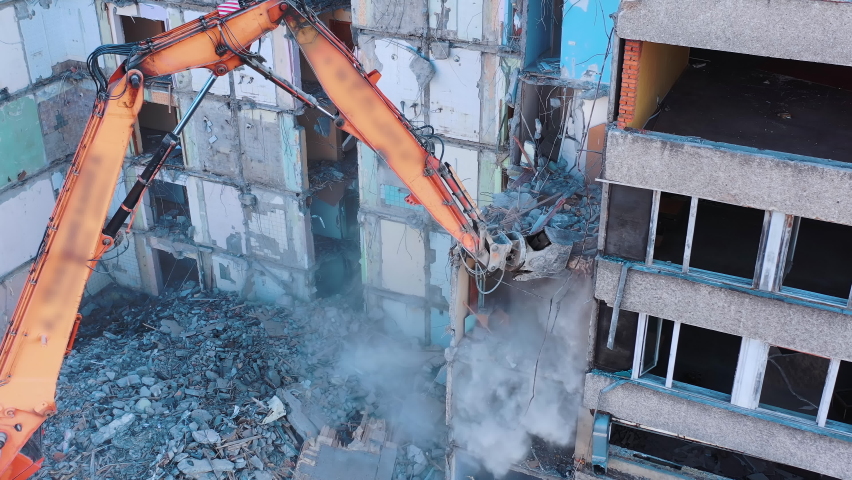 Demolition machine is breaking the floors into pieces and throwing them down. Powerful claw of excavator demolishing the ruined building. | Shutterstock HD Video #1084739971