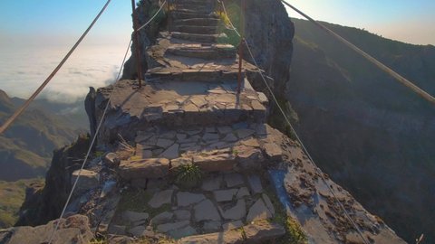 Footage of an extreme walk on a narrow mountain path with a cliff underfoot over the clouds in Madeira islands. Walking trail from Pico Ruivo to Pico do Areeira