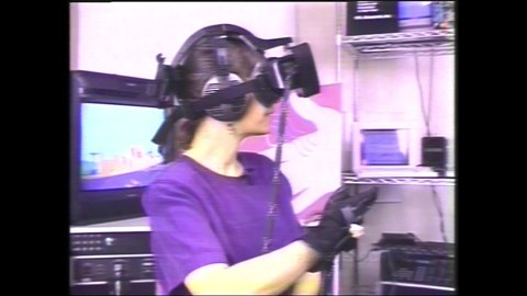 1980s Cupertino, CA. Woman using early version of Virtual Reality headset   know as haptic technology, 3D touch, or kinaesthetic communication. 4K Scan of Vintage Archival Betacam Master
