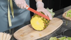 Young woman in the kitchen cuts fresh ripe pineapple. Vegetarian concept
