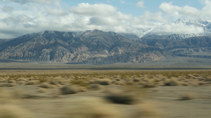 Road trip to Death Valley, driving auto in California, USA. Hitchhiking traveling in America. Highway, mountains and dry desert, arid climate wilderness. Passenger POV from car. Journey to Nevada. Royalty-Free Stock Footage #1084758952