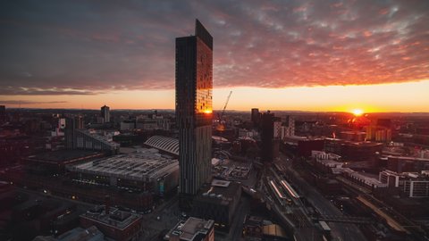 Establishing Aerial View Shot of Manchester, City Skyline, England United Kingdom, slowly circling around iconic skyscraper, sun wakes up city