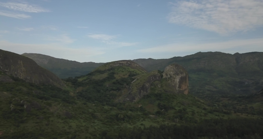 Aerial drone footage of a tropical landscape, with forest and mountains Kumbira forest reserve, small village and huge geologic rock elements, on Conda, Sumbe, Angola...