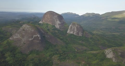 Aerial drone footage of a tropical landscape, with forest and mountains Kumbira forest reserve, small village and huge geologic rock elements, on Conda, Sumbe, Angola...