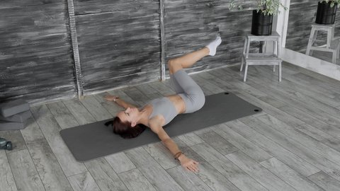 Brunette woman making abs exercises. Young sporty woman training abdominal muscles on mat. Fitness woman working out for better health indoors. Bodycare and fitness concept. 4K, UHD