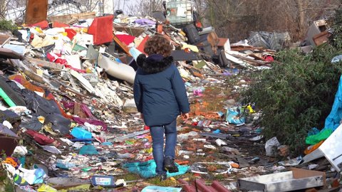 Europe, italy , Milan 7-year-old boy walks in the middle of an illegal and abusive landfill of polluting waste of various kinds - climate change, global warming and air pollution of the planet earth