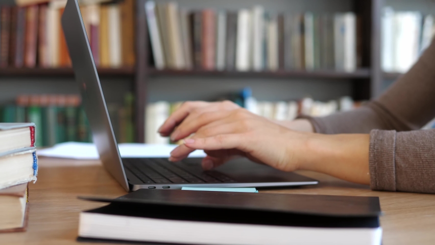 College student uses a laptop to watch online distance learning, a seminar, a distance university webinar, or conduct a virtual classroom meeting in the university's creative space. The girl works on Royalty-Free Stock Footage #1084768000