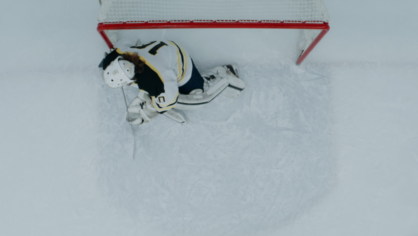 OVERHEAD HIGH ANGLE Goalie makes a save after the shot during the hockey game. Shot with 2x anamorphic lens Royalty-Free Stock Footage #1084768933