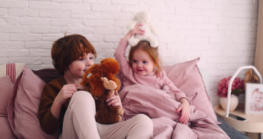 cheerful happy kids playing with stuffed animal toys on the bed in the morning, kids having fun at home Royalty-Free Stock Footage #1084770454