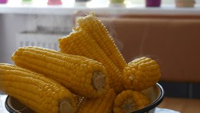 Boiled corn in a large bowl in the home kitchen. Steam comes out