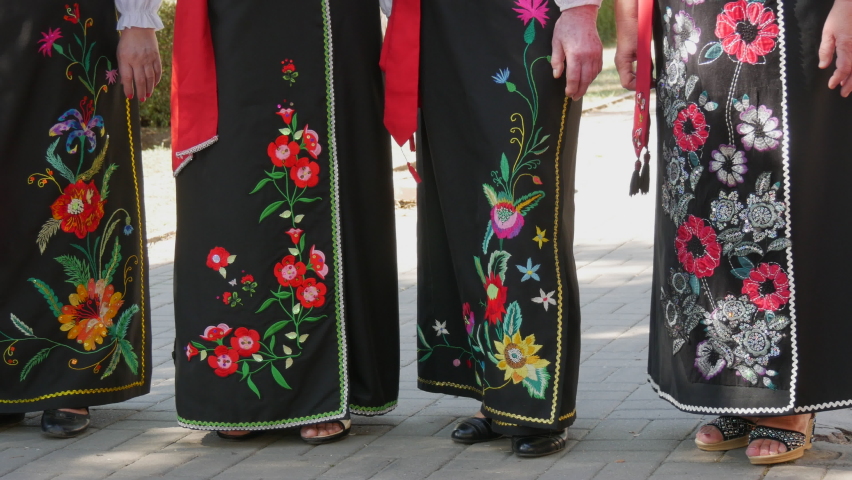 Ukrainian national long black skirts embroidered with floral ornaments, flowers, leaves. A group of women in national costumes stands on the street in summer