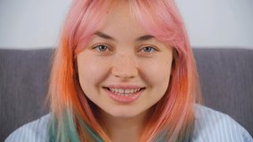 Cute young woman with dyed hair looking in camera. Pretty white girl with colored hair posing with wow expression. Video portrait of Caucasian female with pink hair filmed in 4k stock video