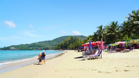 Umbrellas on beach and Coconut palm trees in island. Beach after covid-19, Coronavirus epidemic. Phuket sea popular destination famous beaches Thailand. Video 4k copy space 2022.