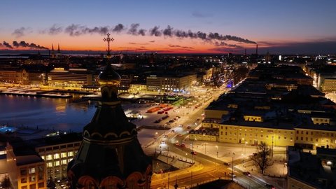 Aerial view around the Uspenski cathedral overlooking the illuminated market square, night in Helsinki - circling, drone shot