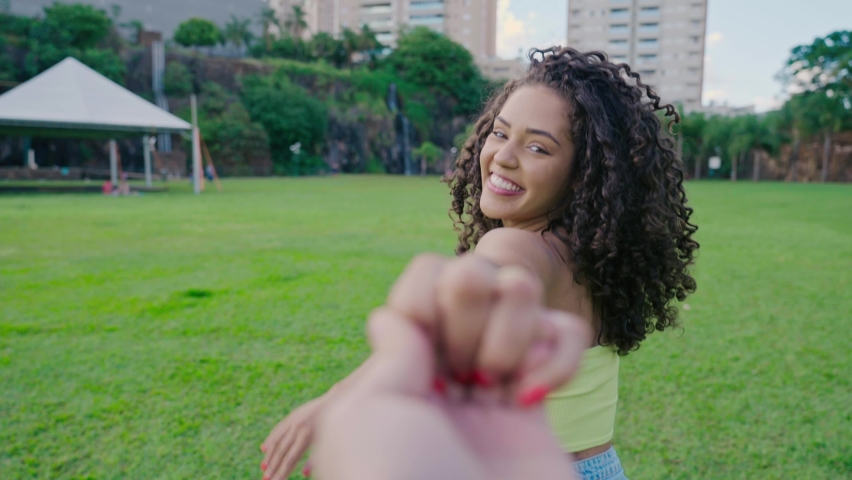 Follow me concept. Male following girlfriend holding hands in a park. POV. Happy young Latin woman leading her boyfriend in slow motion. Getting to know the park. Tourism. 4K. Premium Cinematic Video. | Shutterstock HD Video #1084780264