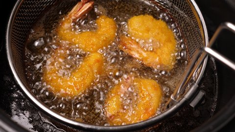 Cooking tempura shrimps in deep fryer. Closeup
