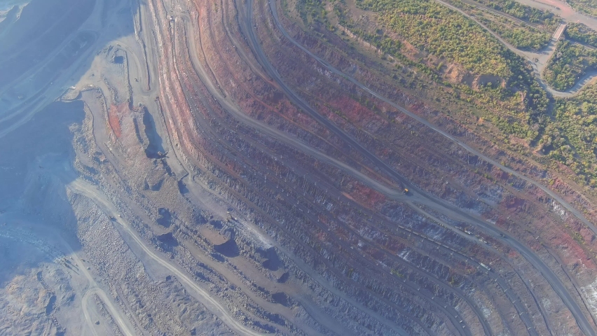 Open pit mining for steel production. A giant iron ore quarry. Aerial view of an open pit. Extraction of ore from the bowels of the earth. Environmental damage to industry. Drone video