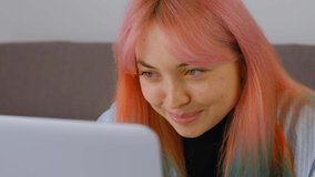 Beautiful excited white woman working on laptop computer with happy smile. Caucasian girl with dyed hair networking. Creative professional female doing distant work on notebook pc filmed in 4k