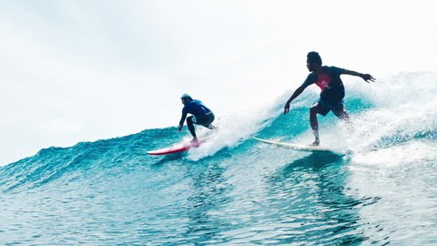 MALE, MALDIVES - OCTOBER 2021: Tourist surfer drops in local Maldivian surfer. Two surfers ride one ocean wave - surfing etiquette violation
