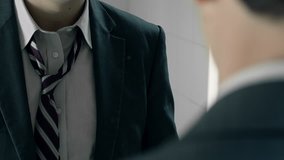 confident businessman at the mirror adjusting his necktie