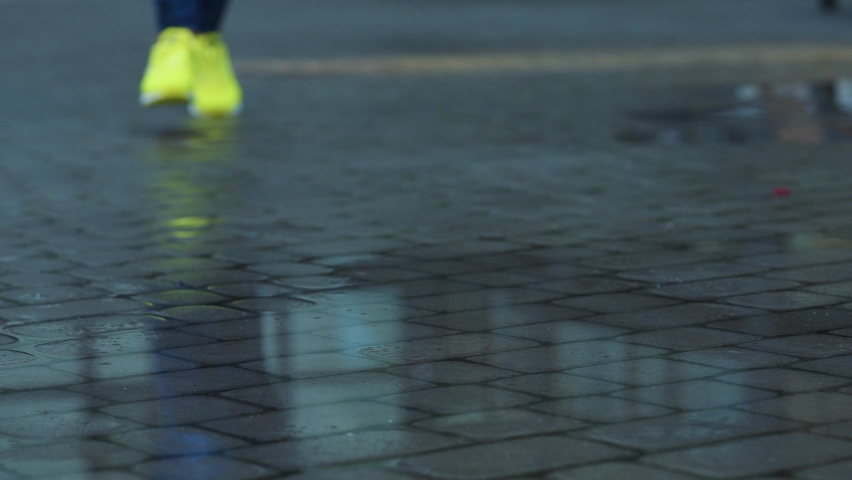 Female sports woman jogging outdoors, stepping into puddle. Single runner running in rain, making splash. Slow motion