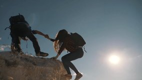 Teamwork. A couple of tourists lend a helping hand while climbing the cliff to the top of the mountain. The path to success in teamwork. Family hiking. A helping hand to overcome difficulties. - Powered by Shutterstock - Get 15% off with code: PIKWIZARD15
