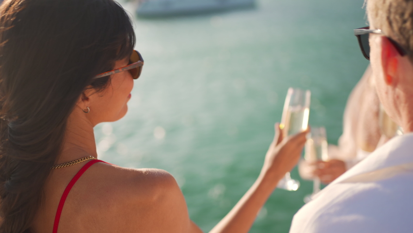 Group of man and woman friends enjoy party drinking champagne with talking together while catamaran boat sailing at summer sunset. Male and female relax outdoor lifestyle on tropical travel vacation | Shutterstock HD Video #1084813324