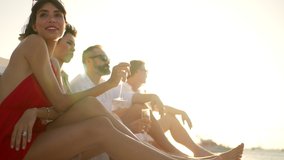 Group of man and woman friends enjoy party drinking champagne with talking together while catamaran boat sailing at summer sunset. Male and female relax outdoor lifestyle on tropical travel vacation - Powered by Shutterstock - Get 15% off with code: PIKWIZARD15