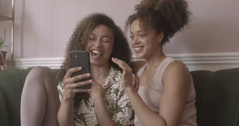 Two female friends laughing whilst using a smartphone