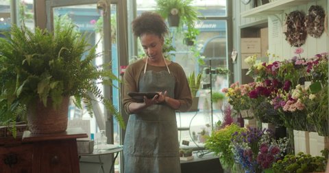 Young Female Small Business Owner, Florist taking inventory with digital tablet in Flower shop