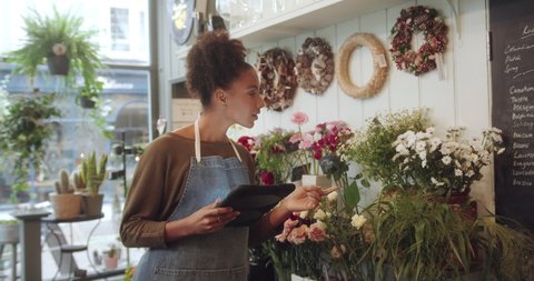 Female Small Business Owner, Florist taking Inventory with Digital tablet in Flower Shop