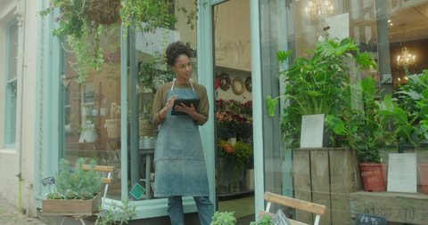 Black Female Small Business Owner, Florist taking inventory with Digital tablet at Flower shop